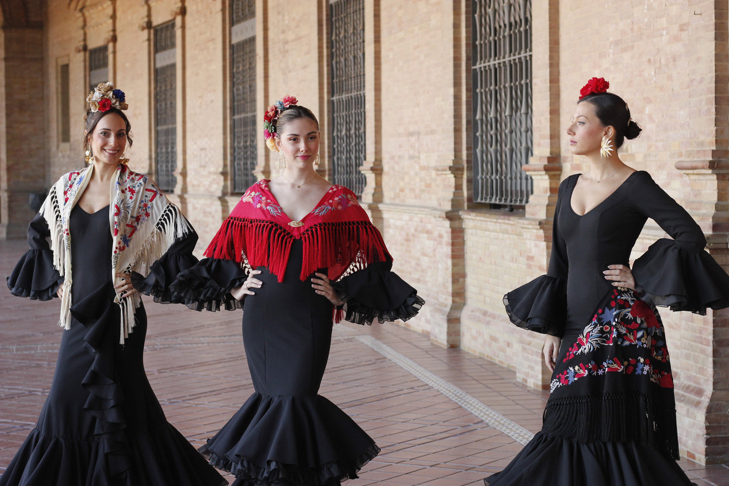 El vestido de flamenca negro Clavel con mantón y complementos, incluyendo el ramillete Rojo Pasión y pendientes dorados Hinojos, es el conjunto perfecto para brillar en la Feria de Abril con estilo y sofisticación.