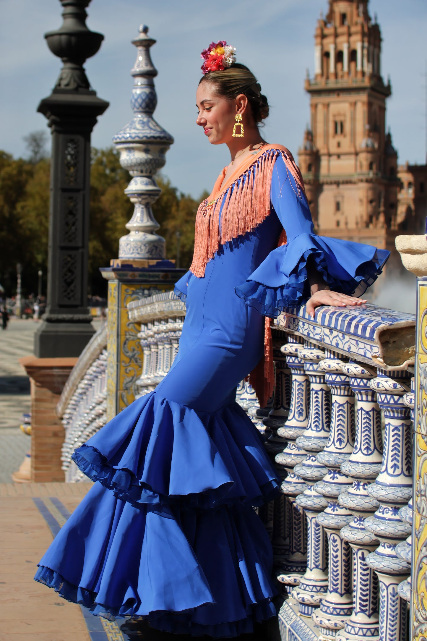 Descubre el manton Noa en mandarina con flores buganvilla. Elaborado en algodón con flecos de seda, es ideal para destacar en ferias y romerías.