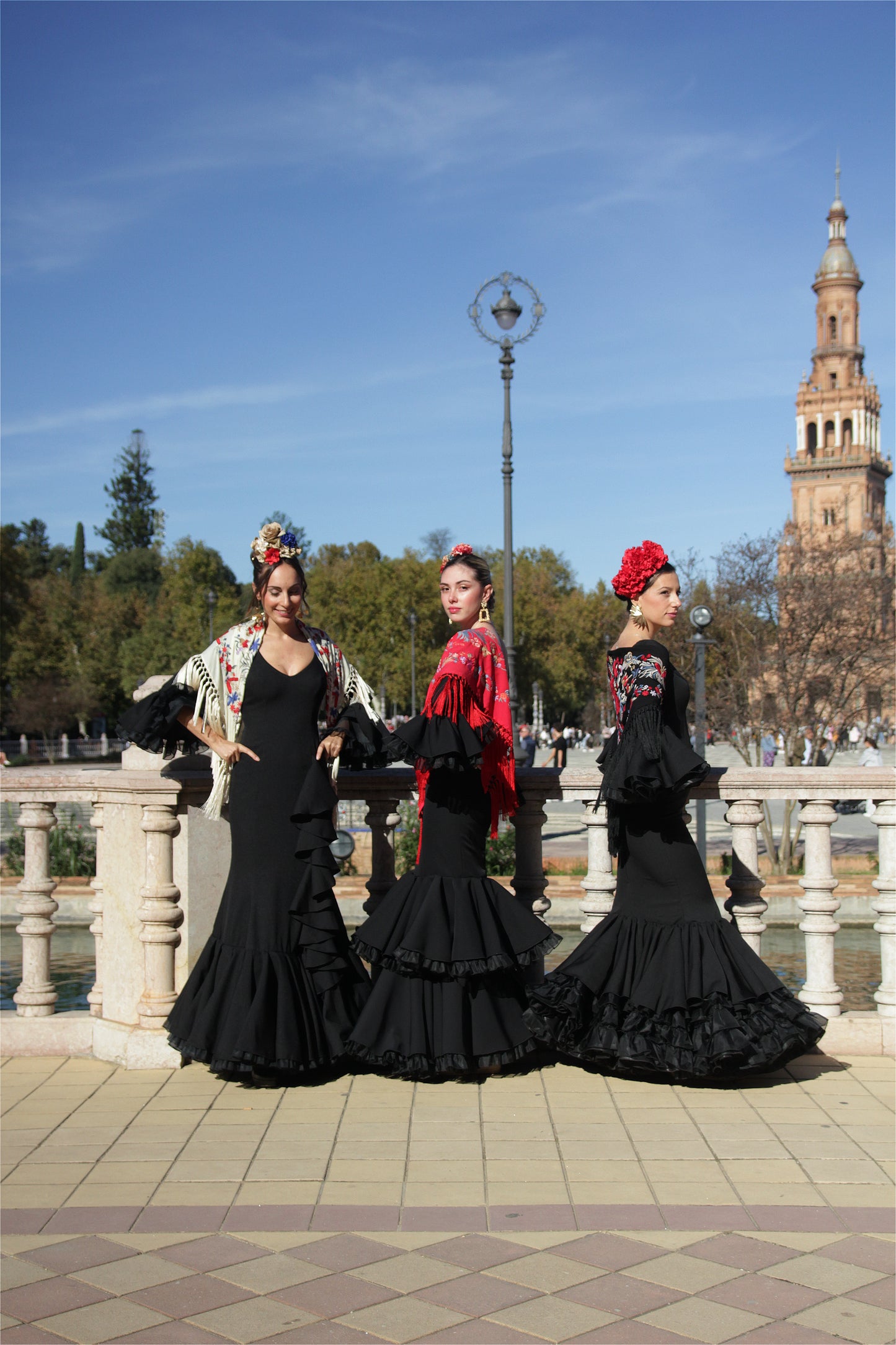 Con el vestido de flamenca negro Clavel, mantón con flor roja, ramillete Rojo Pasión y pendientes dorados Hinojos, este look es todo lo que necesitas para destacar en la Feria de Abril con elegancia y dinamismo.
