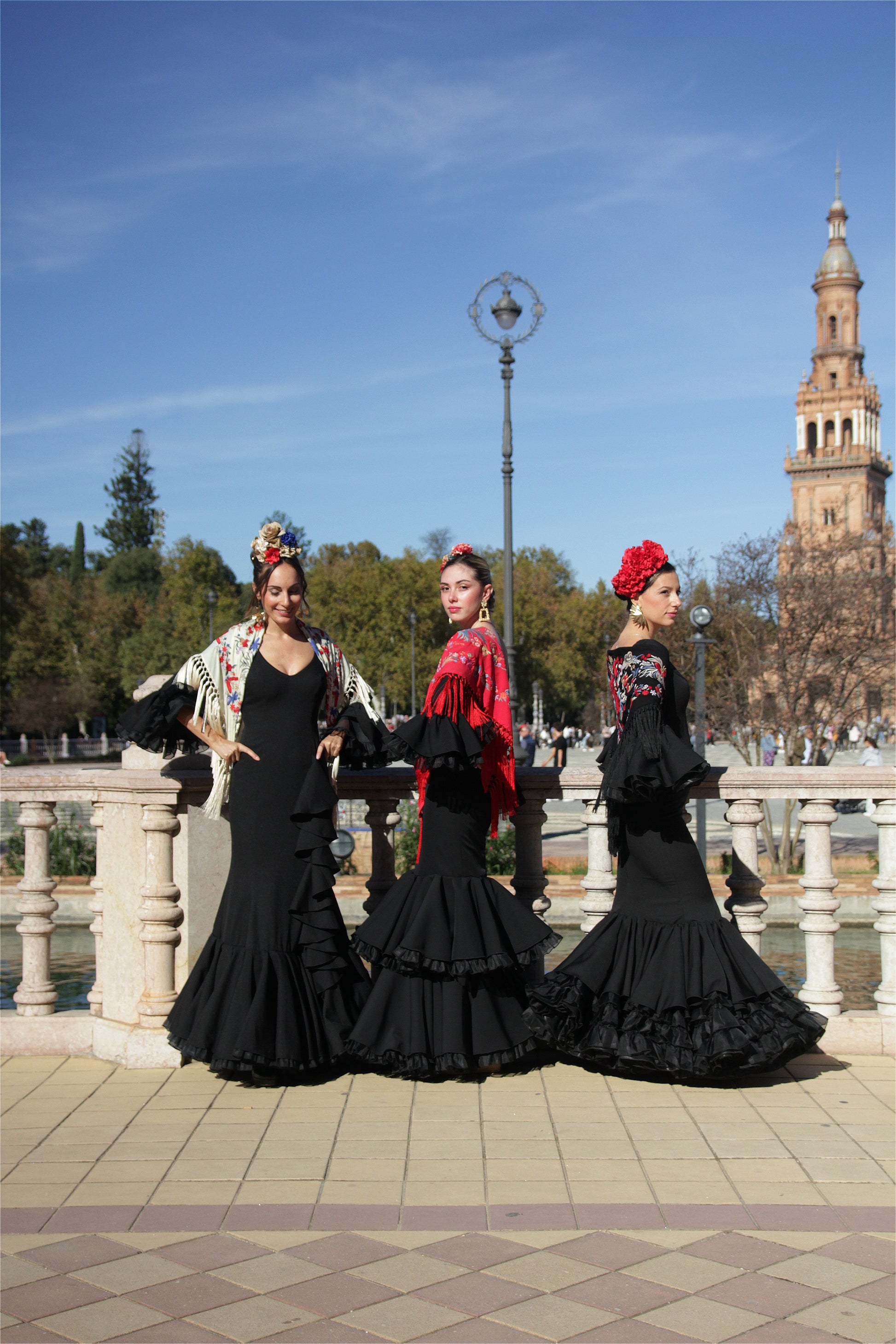 Con el vestido de flamenca negro Clavel, mantón con flor roja, ramillete Rojo Pasión y pendientes dorados Hinojos, este look es todo lo que necesitas para destacar en la Feria de Abril con elegancia y dinamismo.