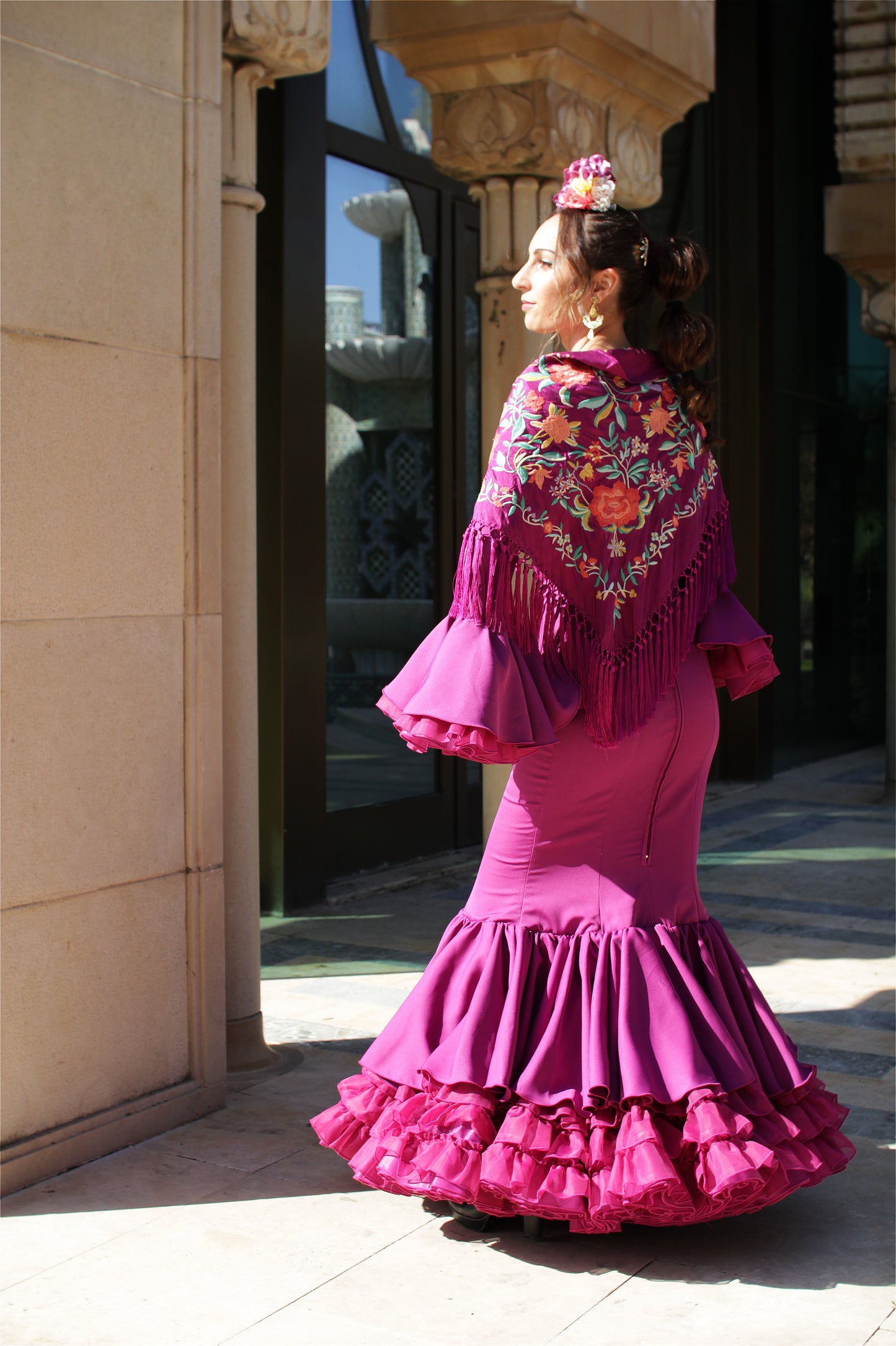Vive la Feria de Abril con pasión y elegancia. Traje de flamenca buganvilla, mantón buganvilla, ramillete Jaleo y pendientes dorados Nerja para un look flamenco único, lleno de movimiento y sofisticación.