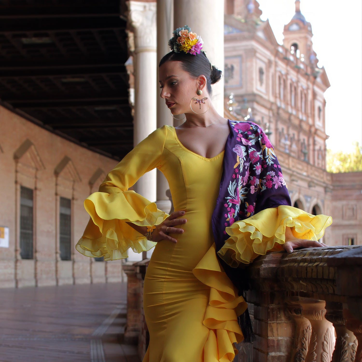 Look de feria de abril con vestido de flamenca amarillo, acompañado de mantón, pendientes y ramillete de flores, un conjunto completo y elegante para destacar en romerías y ferias