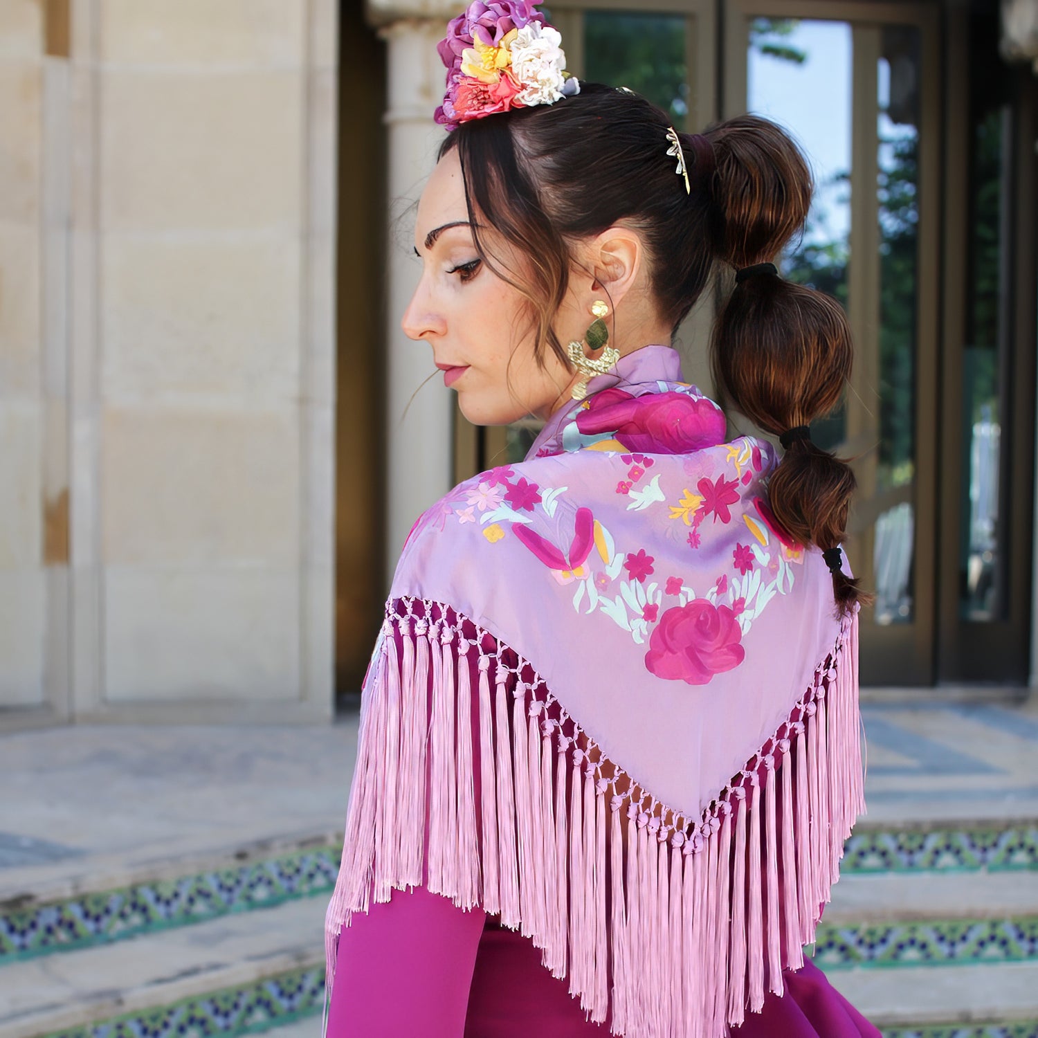 Look de feria de abril con traje de flamenca buganvilla, complementado con mantón, pendientes y ramillete de flores, perfecto para un estilo flamenco elegante y vibrante en la temporada de ferias.
