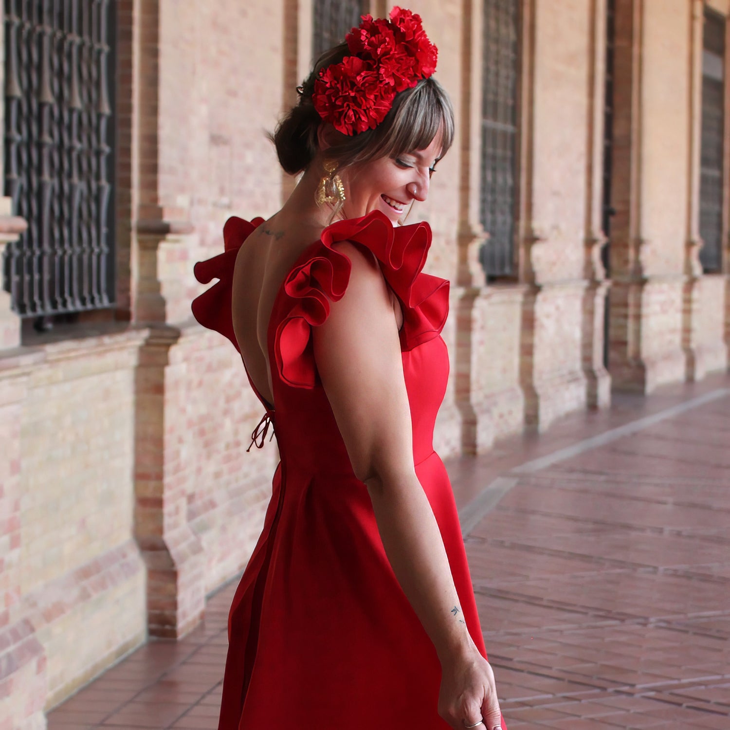 Look de romería con bata de flamenca roja pendientes de flamenca y ramillete de flores, creando un estilo flamenco tradicional y lleno de energía con accesorios flamenca ideales.