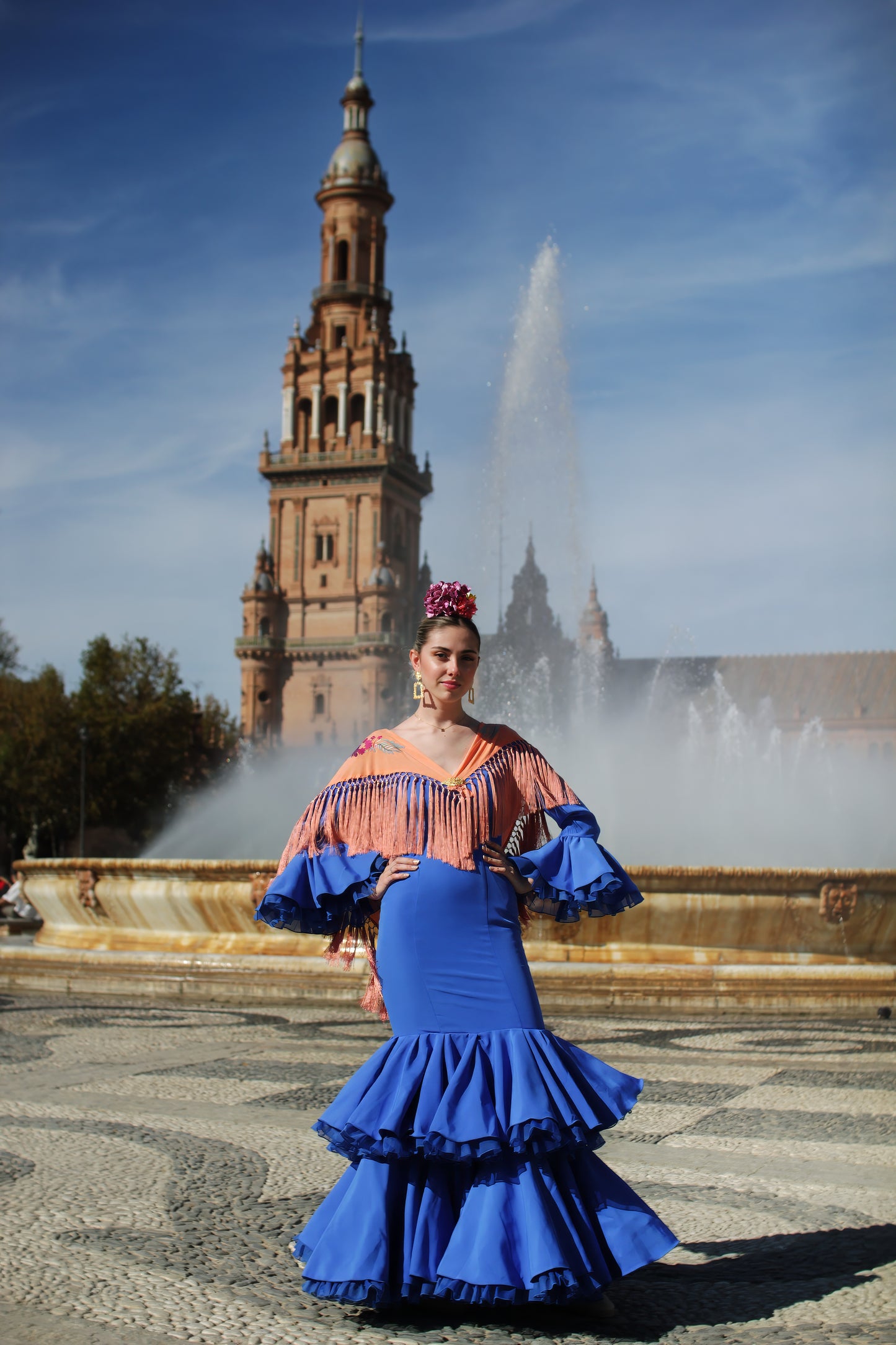 Lleva el estilo flamenco al siguiente nivel con el look completo para la Feria de Abril: vestido azul Jazmin, manton mandarina con flecos de seda, ramillete Jaleo y pendientes Carmona.