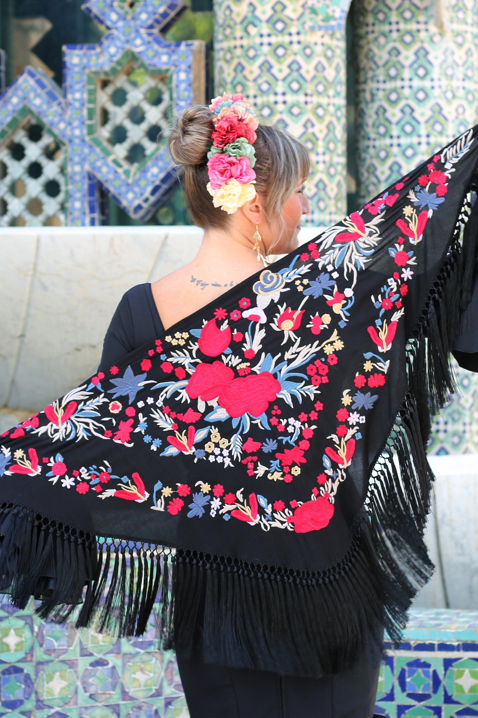 Ideal para ferias y romerías, el manton negro Noa con flores en rojo y azul combina tradición y modernidad en una pieza artesanal única.