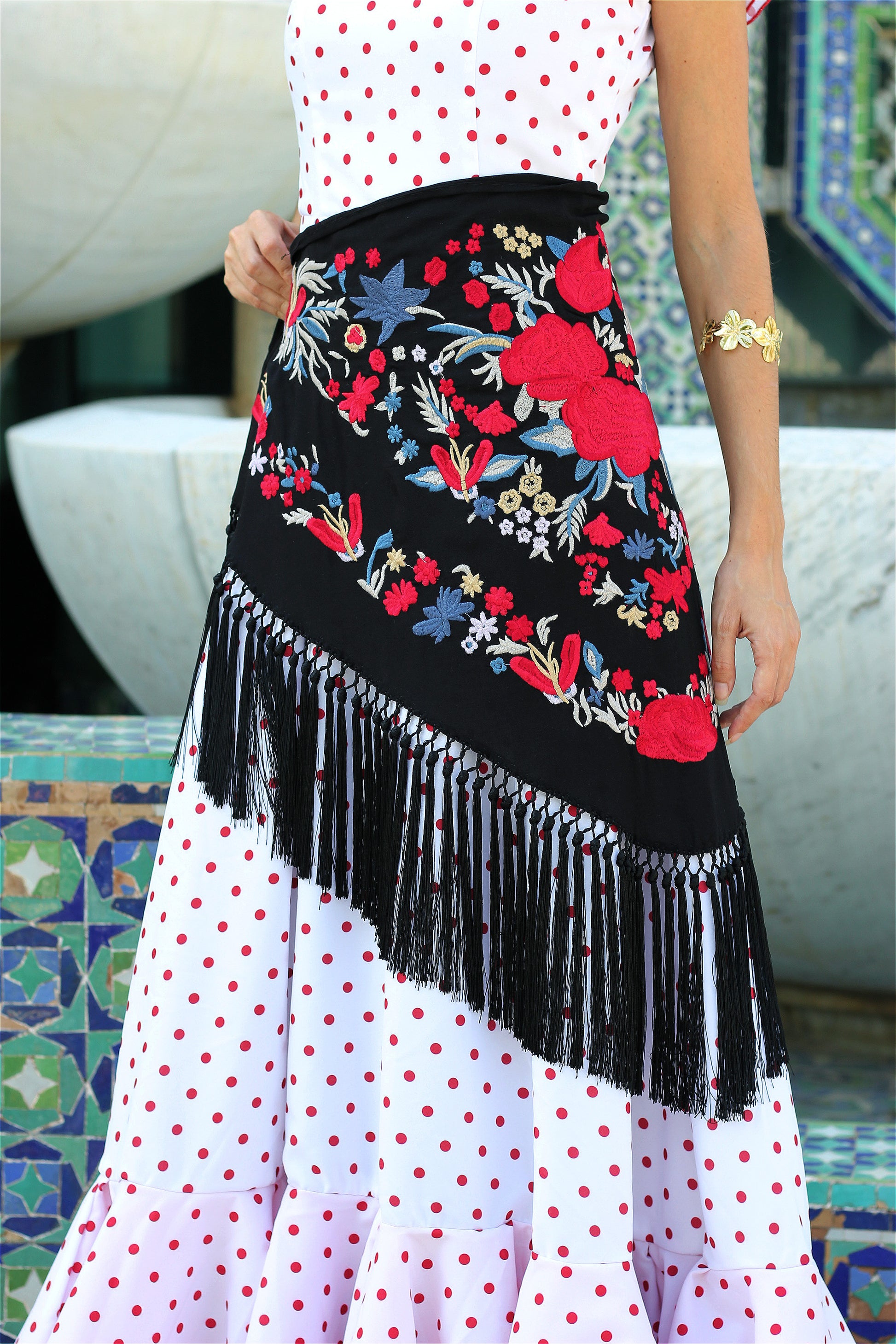 Descubre el manton de flamenca negro Noa con diseño floral rojo y azul. Confeccionado en algodón con flecos de seda, ideal para un estilo impactante.