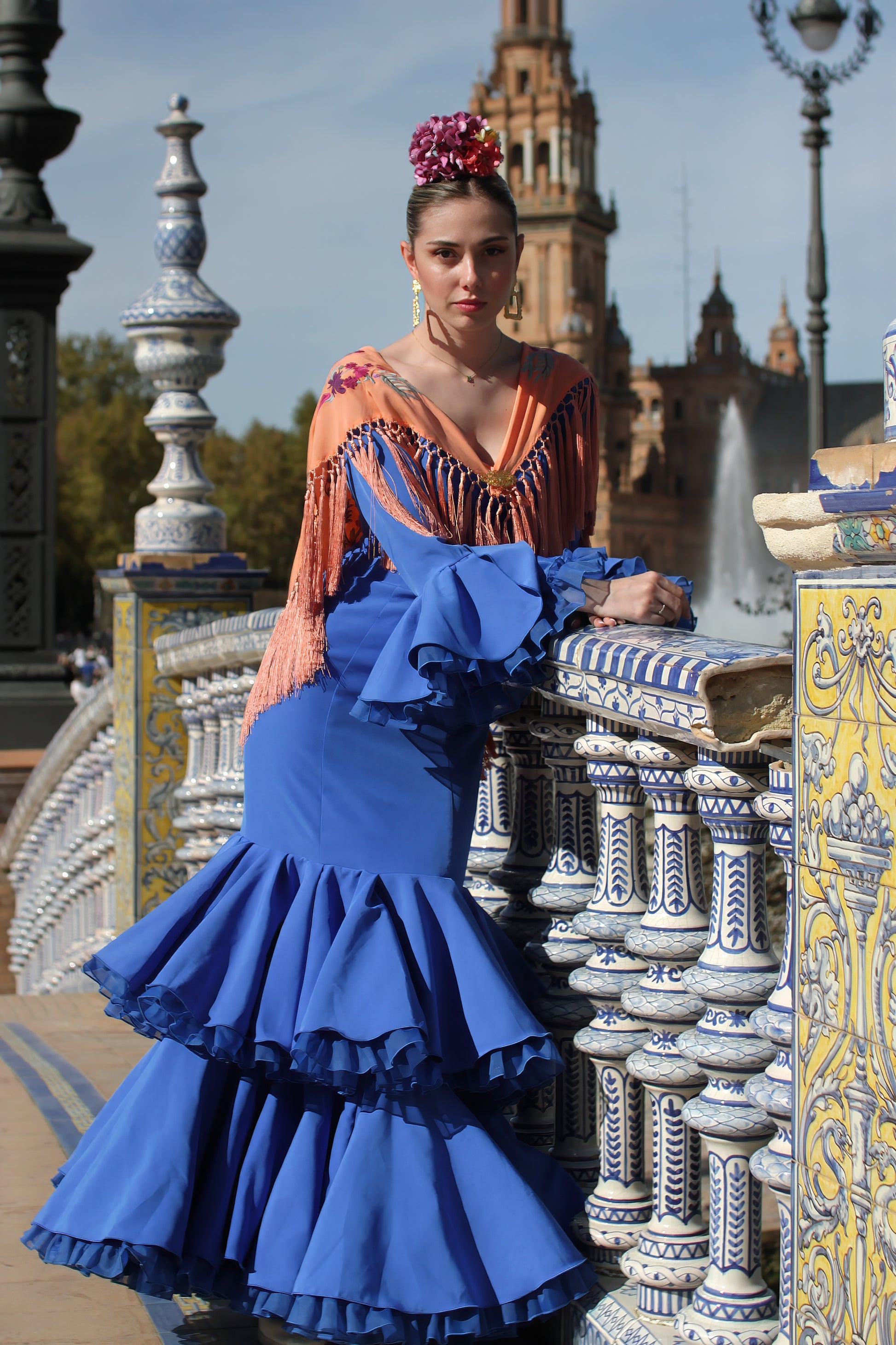 Elegancia y tradición se unen en el manton Noa, mandarina con flores buganvilla. Elaborado en algodón con flecos de seda, ideal para completar tu look flamenco.