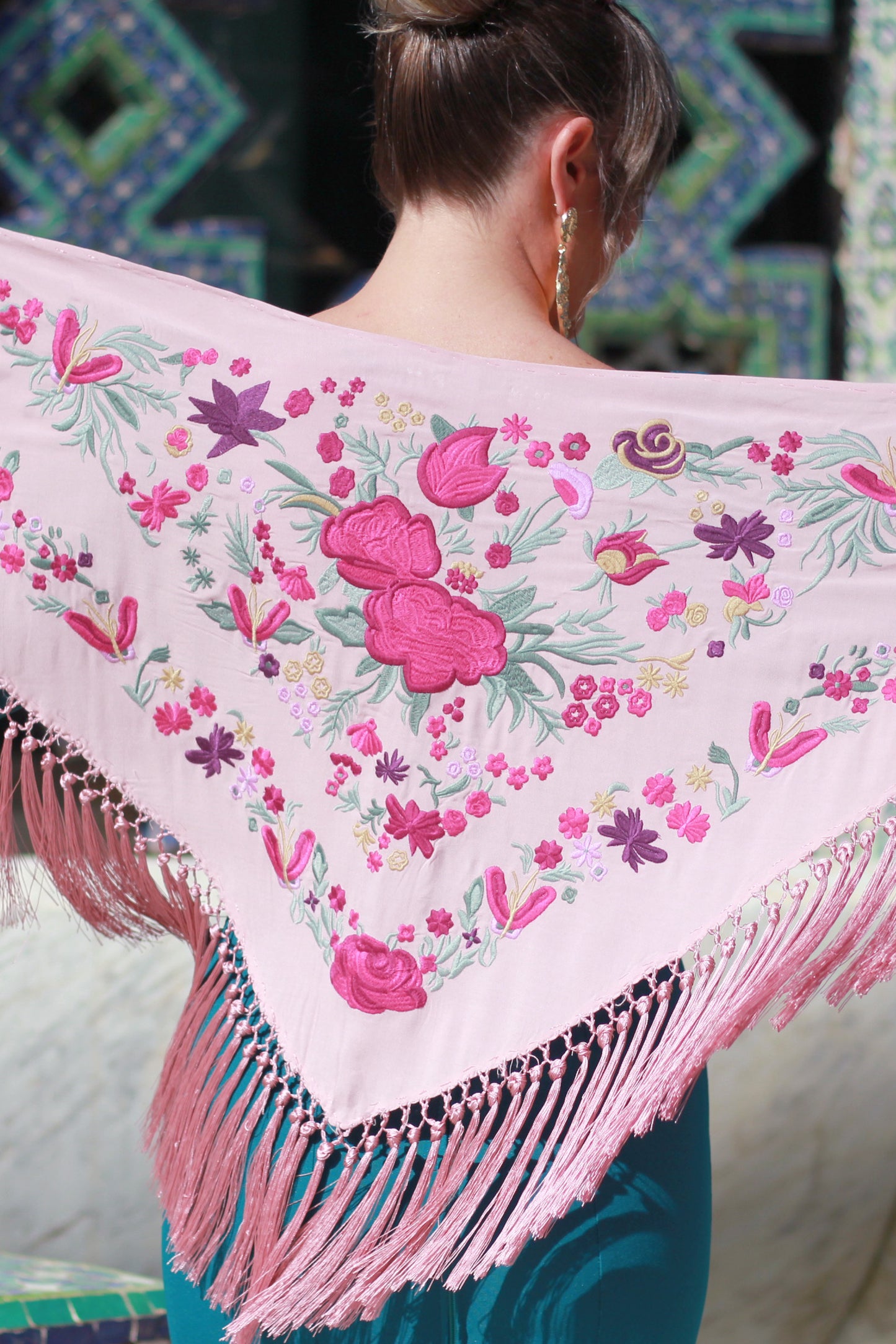 El mantón de flamenca rosa Noa, confeccionado en algodón de alta calidad y flecos de seda, presenta un diseño floral en buganvilla. Hecho en Cantillana, es el complemento perfecto para añadir romanticismo a tu look flamenco.