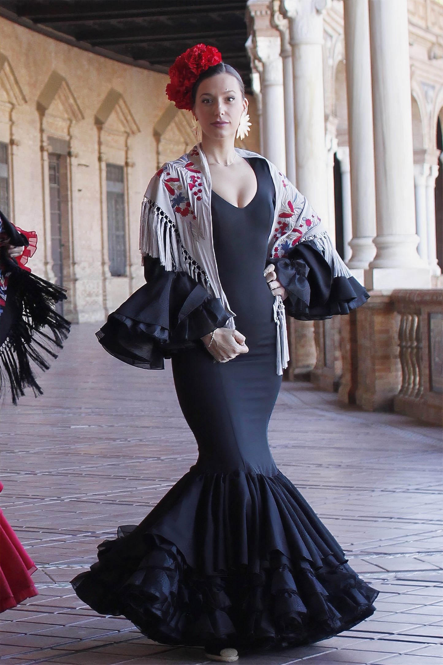 Aporta elegancia a tu estilo flamenco con el mantón gris Noa, elaborado en algodón con un diseño floral en tonos rojos, ideal para cualquier ocasión.