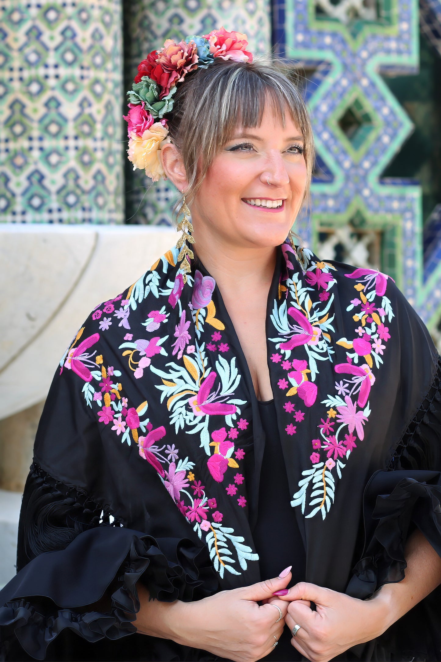 Completa tu look con el manton de flamenca negro Elena, diseñado en seda con flores en tonos buganvilla.