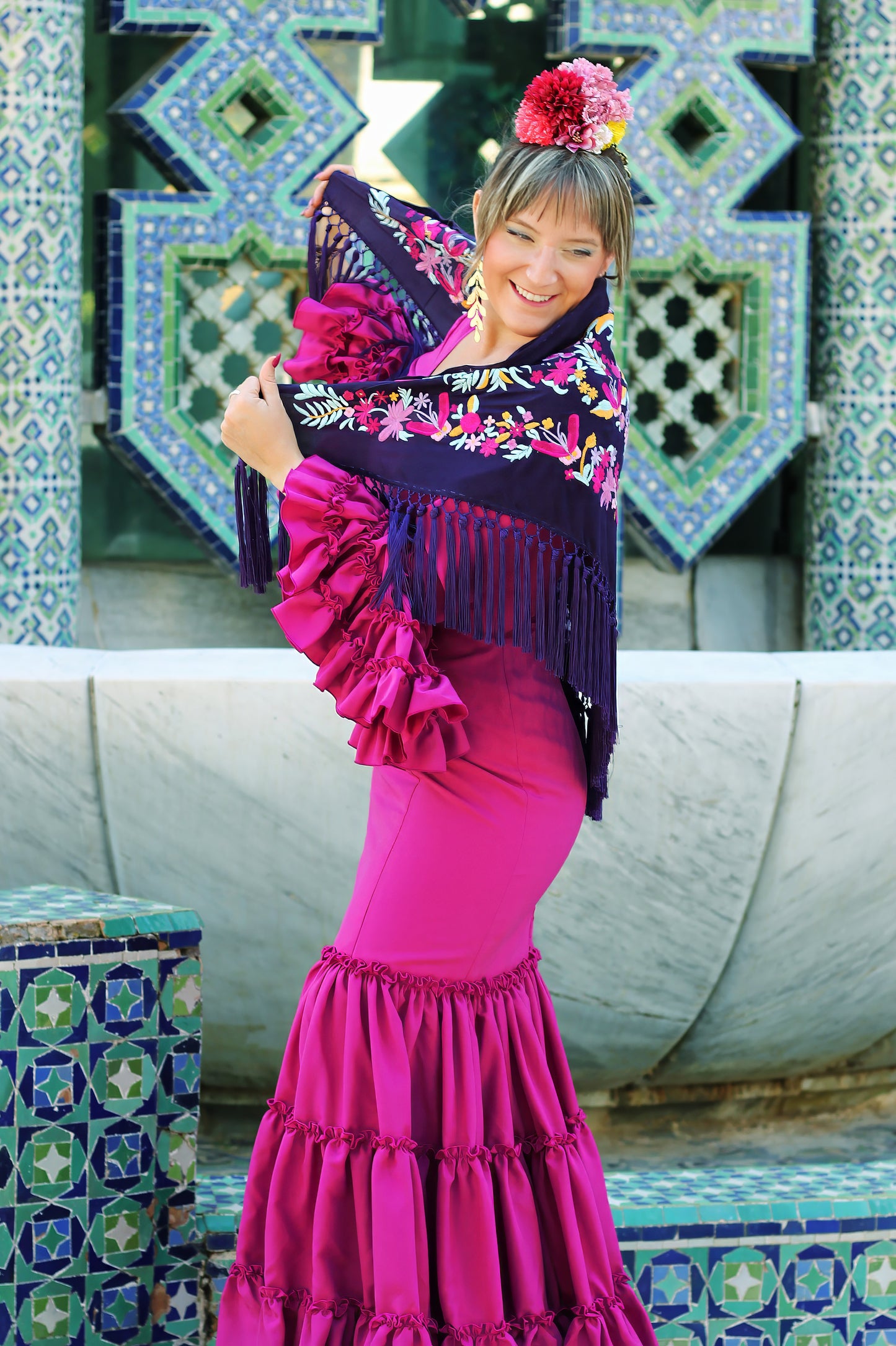Destaca en la feria con el mantón morado Elena, una pieza elegante con flores en buganvilla y amarillo que aportan un toque fresco a tu look