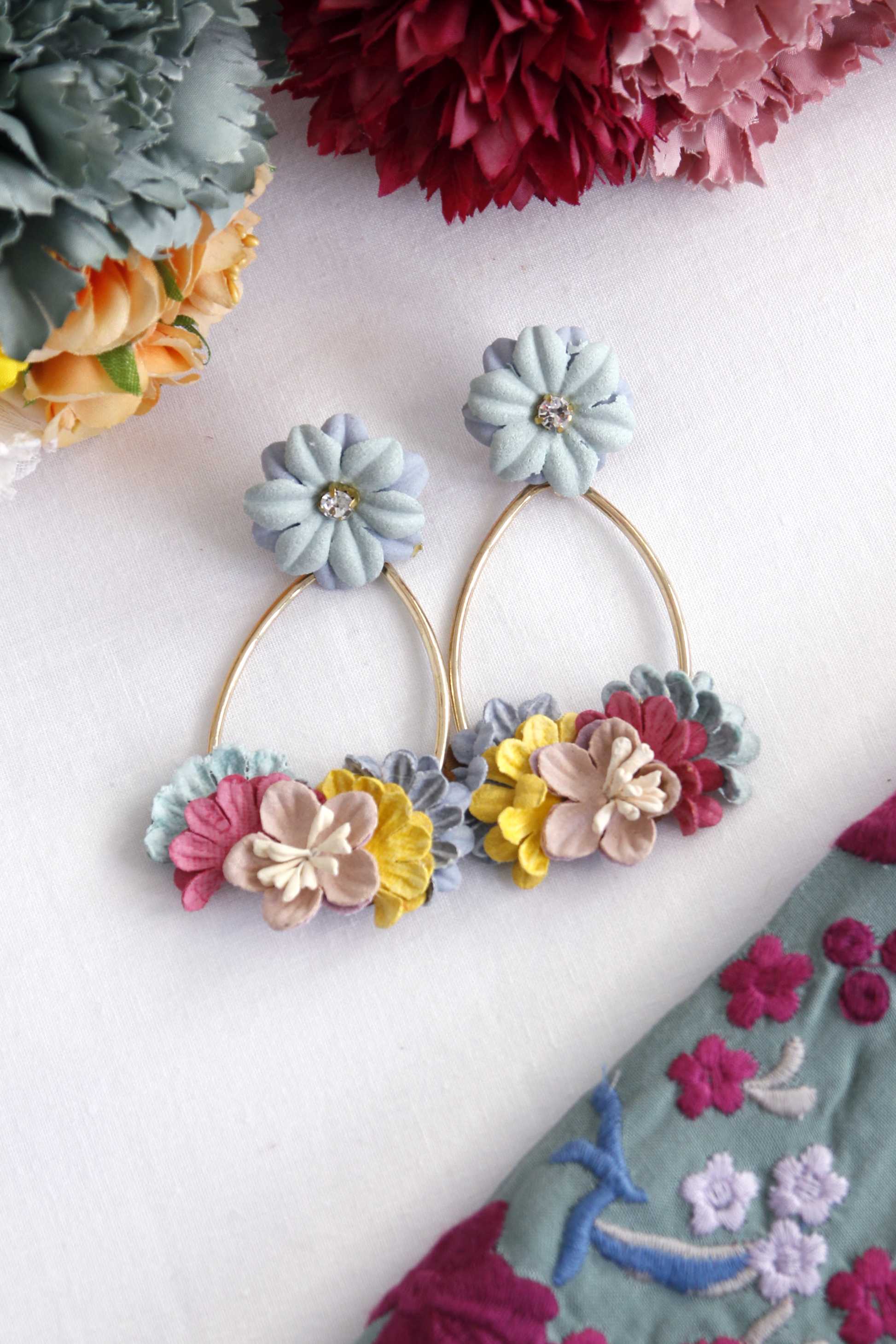 Los pendientes de flamenca Almonte combinan flores coloridas sobre un aro dorado, creando un diseño sofisticado y original que resalta tu estilo flamenco.