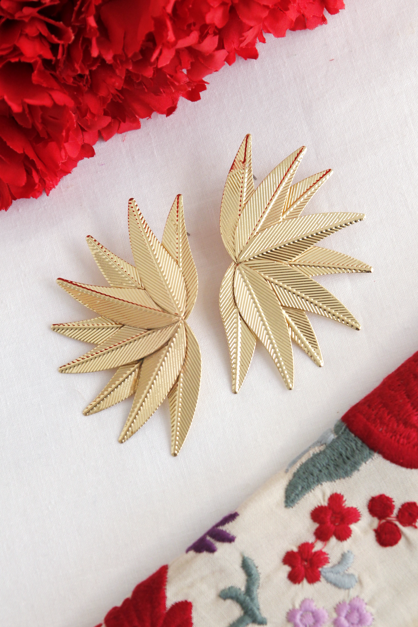 Los pendientes Hinojos, con su elegante diseño floral puntiagudo en dorado, son el accesorio perfecto para aportar sofisticación y glamour a tu look flamenco.