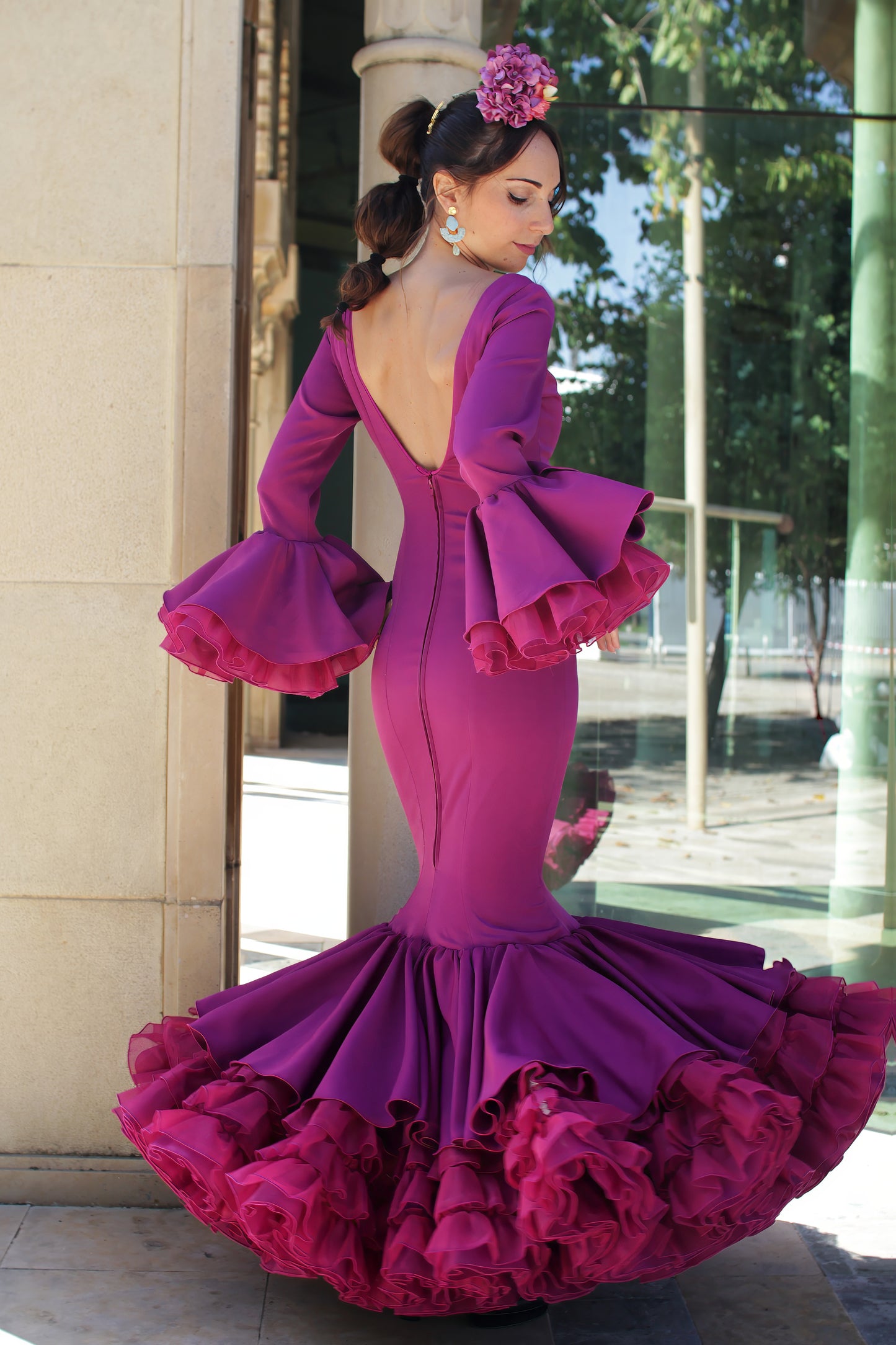 Traje de flamenca Clavel en color buganvilla, diseñado con volantes abundantes y corte sirena que realza la figura, ideal para la Feria de Abril y romerías.