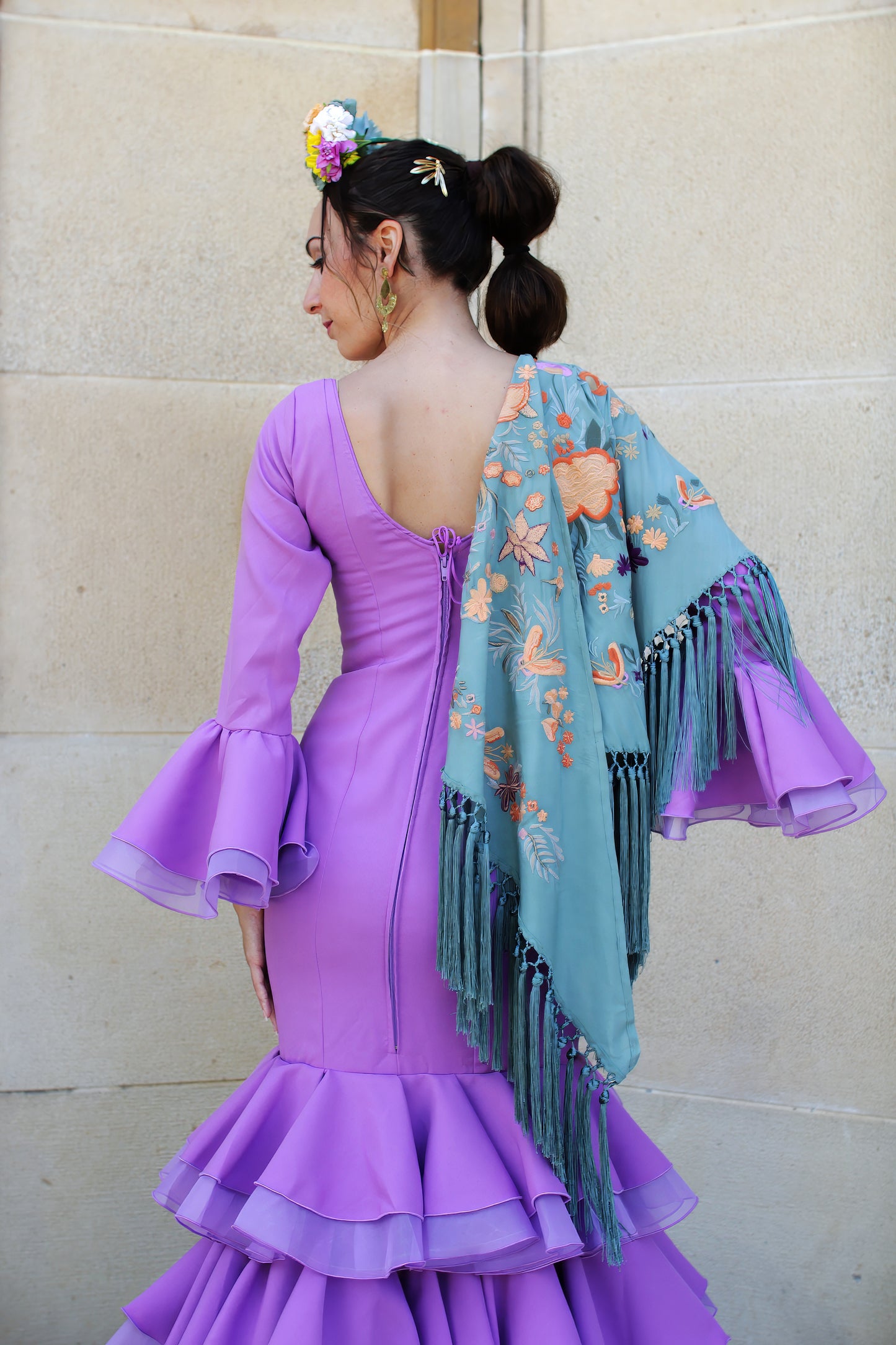 Vestido de flamenca Lavanda en lila con pendientes dorados, ramillete de flores y mantón, ideal para un look flamenco lleno de frescura y estilo.